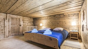 Un dormitorio de cabaña de madera con una cama, dos mesitas de noche y una puerta.
