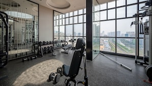 Un gimnasio con amplios ventanales, equipamiento de ejercicio y vistas a la ciudad.