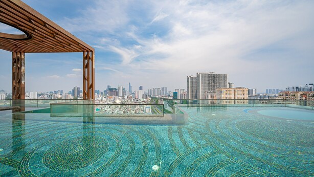 Una piscina infinita en la azotea con vistas a la ciudad, una pérgola de madera y una barandilla de cristal.