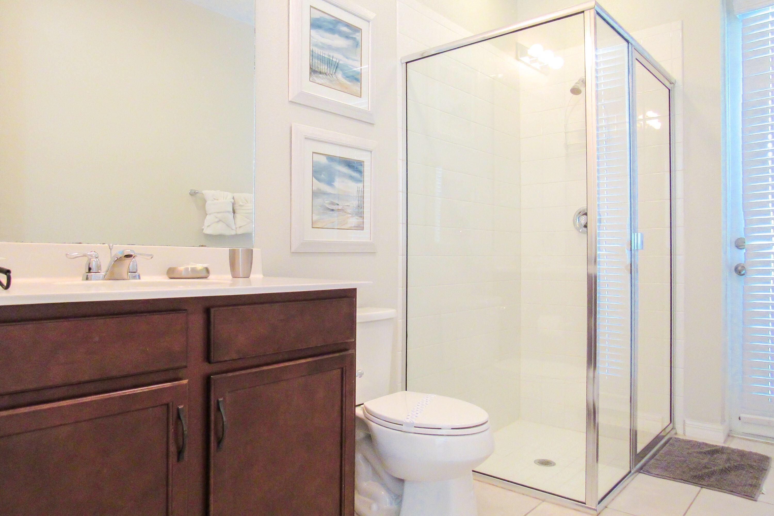 A bathroom with a glass shower enclosure, a white toilet, and a vanity with a mirror.