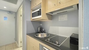 Una cocina moderna con armarios de madera, un lavamanos de acero inoxidable, un microondas integrado y una placa de inducción.