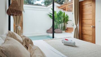 A bedroom with a large bed, a view of a swimming pool, and a wooden door.