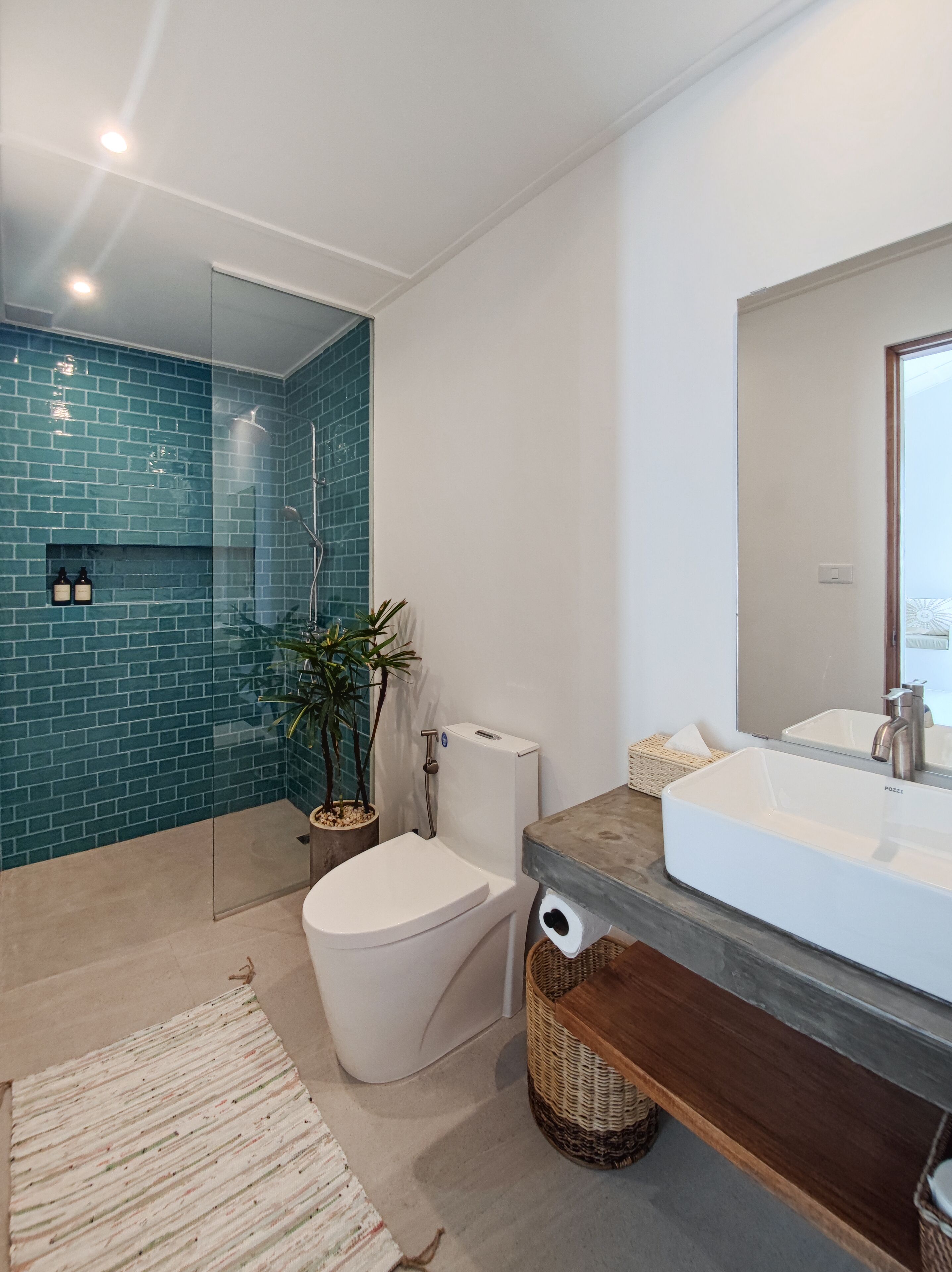 A modern bathroom with a glass shower enclosure, a white toilet, and a large sink with a wooden countertop.