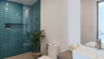 A modern bathroom with a glass shower enclosure, a white toilet, and a large sink with a wooden countertop.