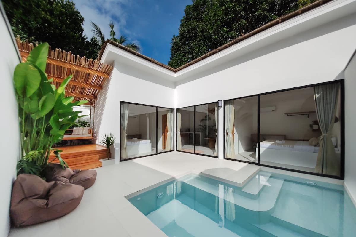A modern house with a swimming pool, large glass doors, and a wooden deck.
