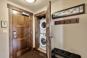 A laundry room with a wooden door, a washing machine, and a bench.