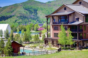 A multi-story building with a pool, surrounded by trees and a mountainous backdrop. - Don't Miss Last Minute Savings! AC, Pool, Hot Tubs (Steamboat Springs)
