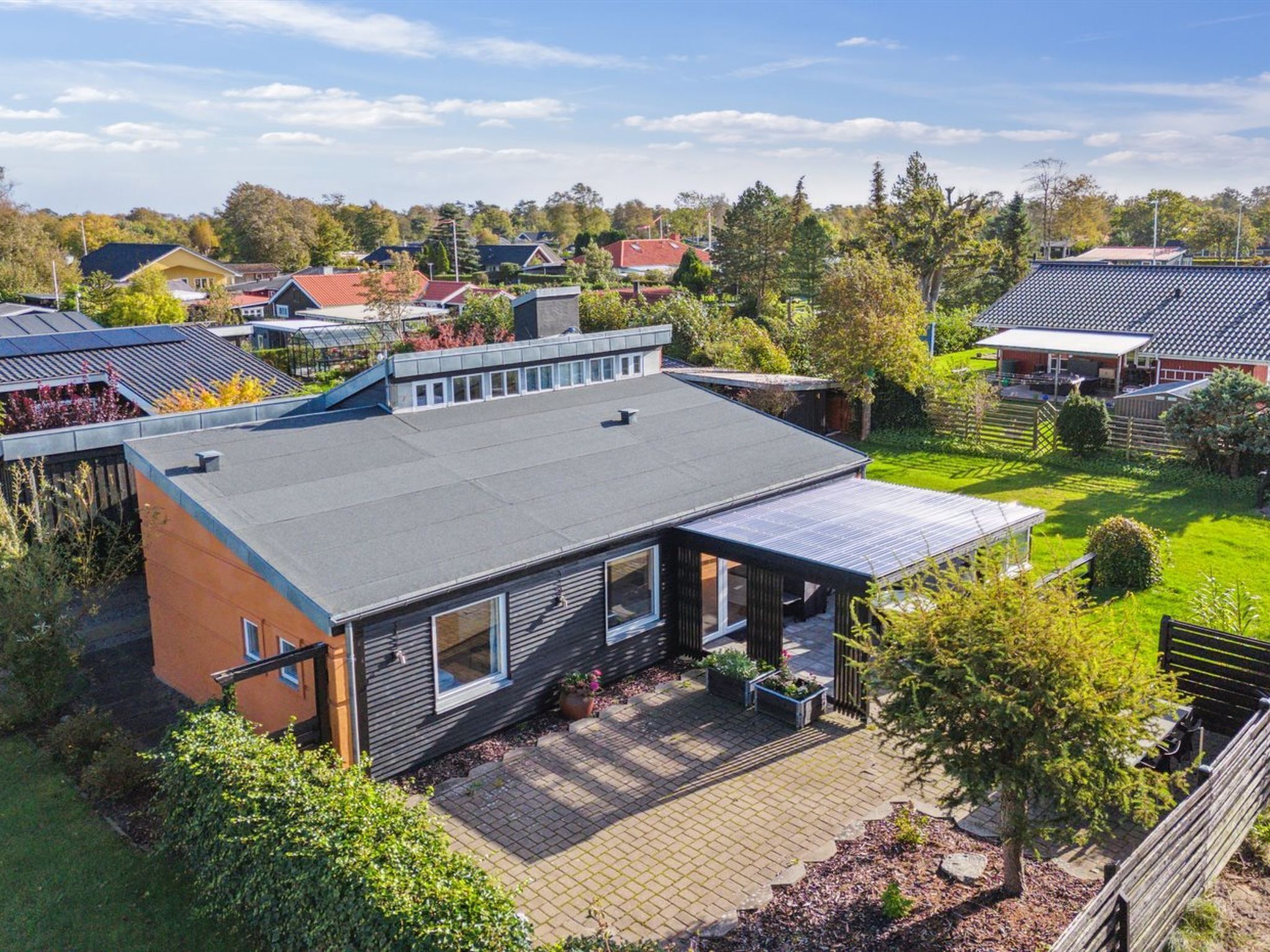 A modern house with a flat roof, solar panels, and a well-maintained garden.