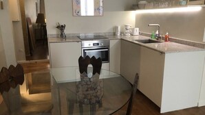 A modern kitchen with a central island, a dining table with chairs, and a kitchen island with a sink and countertop. - Studio à Beaubourg, Paris (Paris)