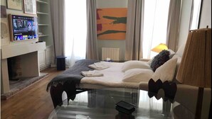 A hotel room with a bed, a TV, a lamp, and a painting on the wall. - Studio à Beaubourg, Paris (Paris)