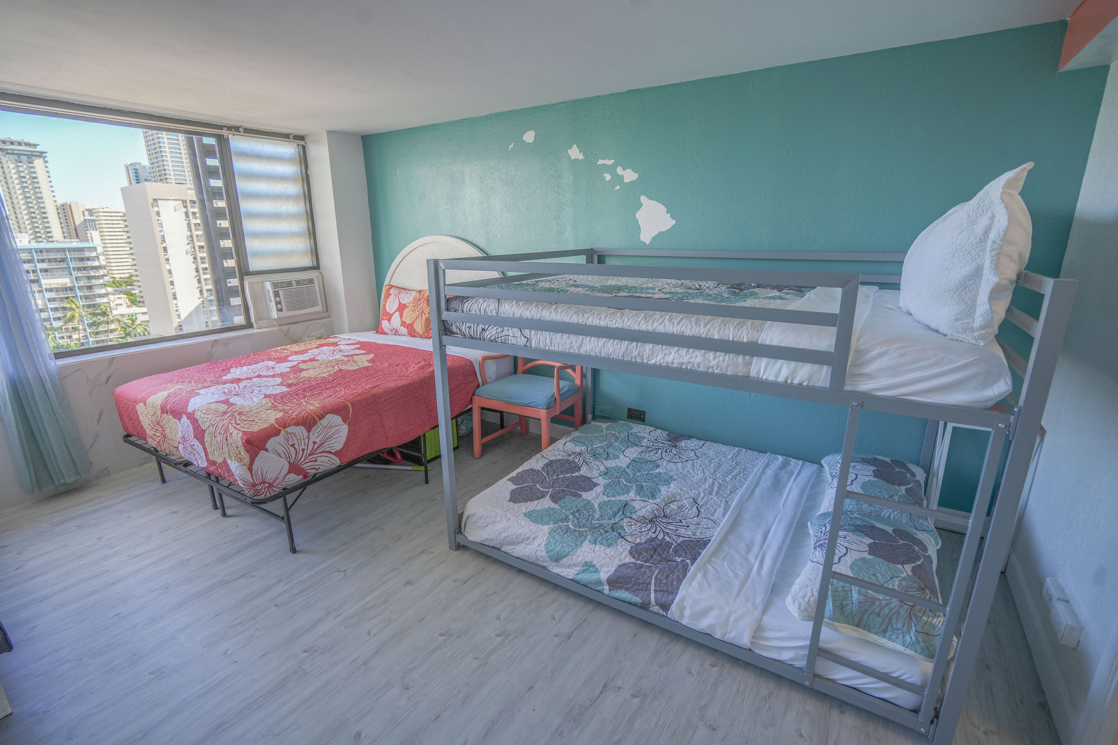 Una habitación con dos literas, una ventana con vista a la ciudad y una silla.