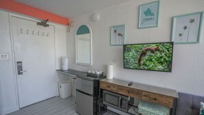 A compact kitchen with a refrigerator, microwave, and a wooden countertop.