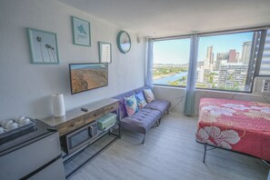 A modern living room with a sofa, a coffee table, a microwave, and a view of the city.