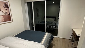 Habitación de hotel con una cama, un escritorio y una puerta corredera que da a un baño.