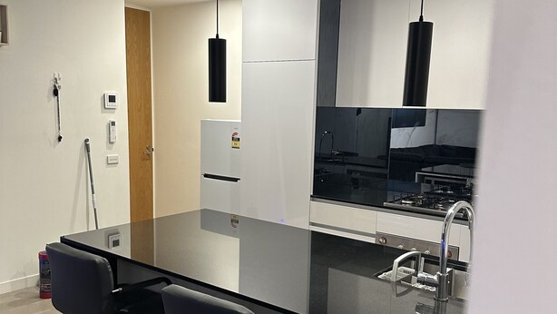 Una cocina moderna con una isla de vidrio, taburetes negros y electrodomésticos de acero inoxidable.