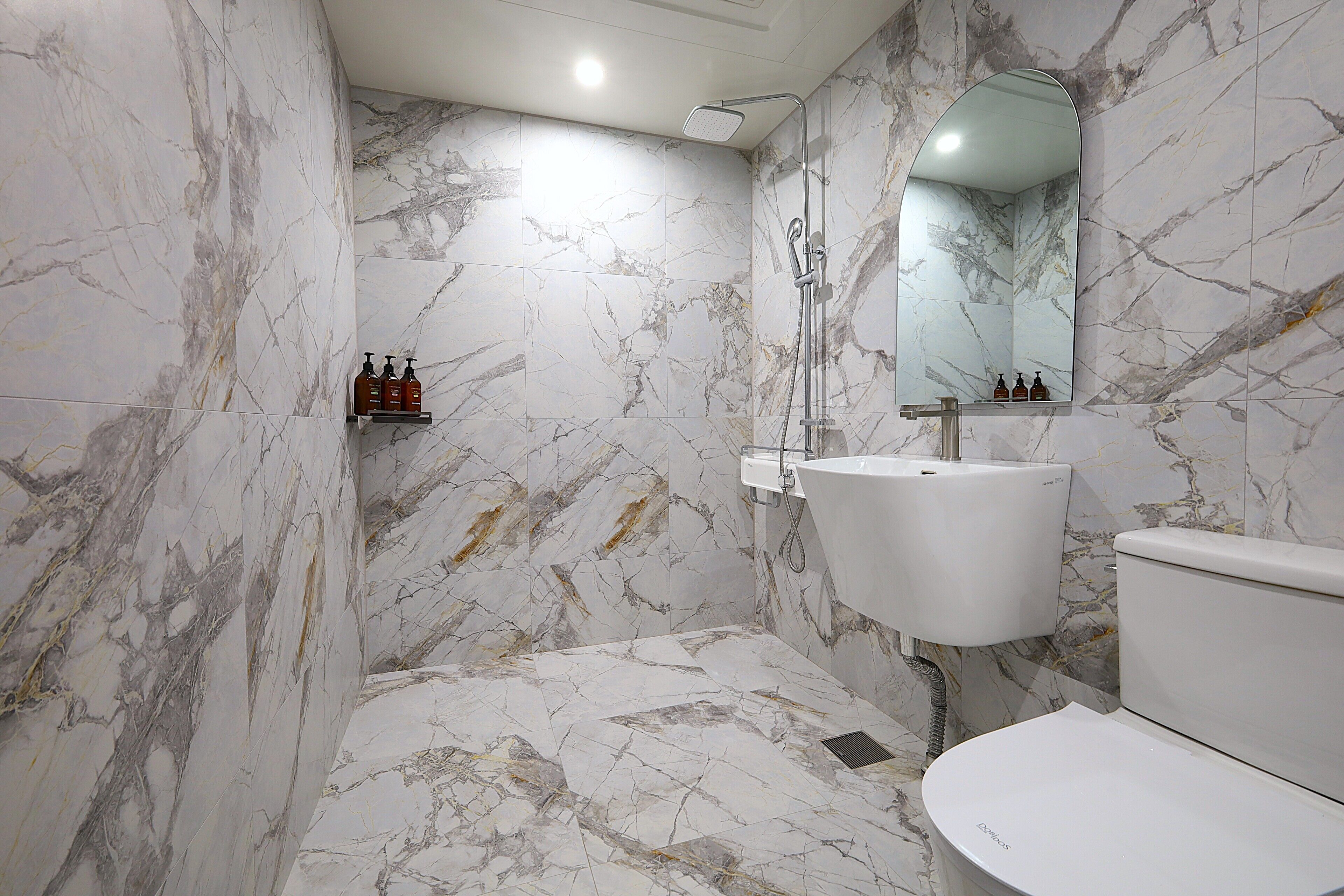 A bathroom with marble walls, a white sink, and a toilet.