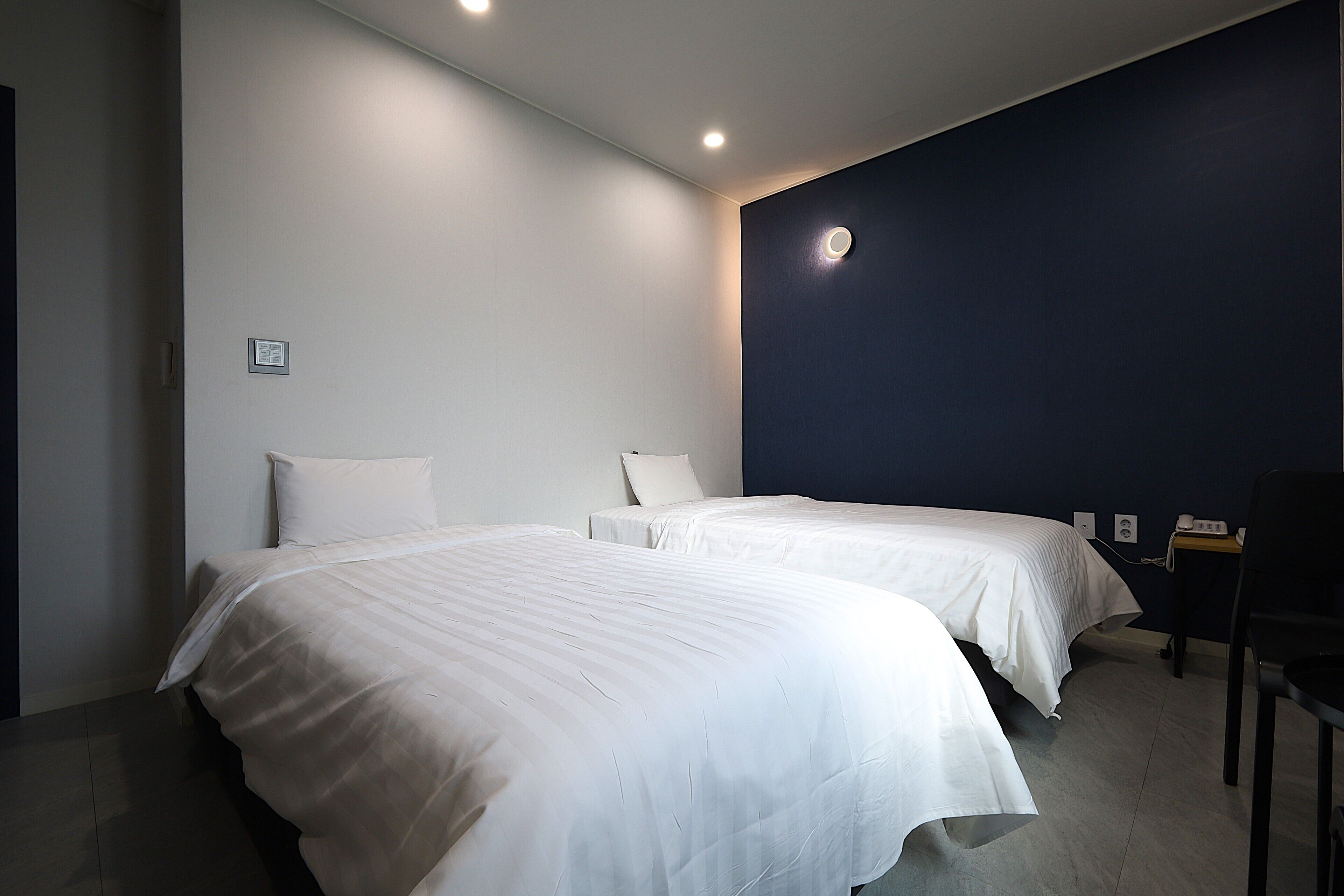 A hotel room with two beds, a desk, and a chair.