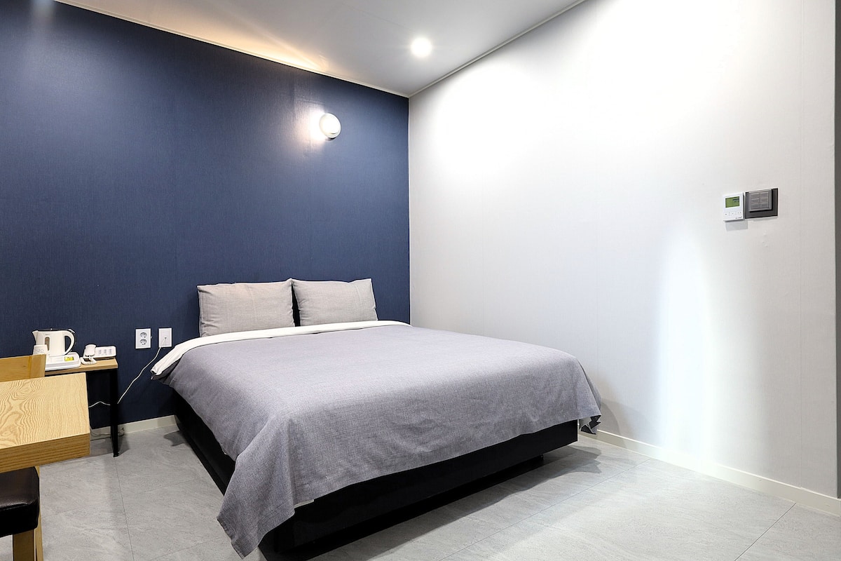 Une chambre moderne avec un lit, une table de chevet et un luminaire fixé au mur.