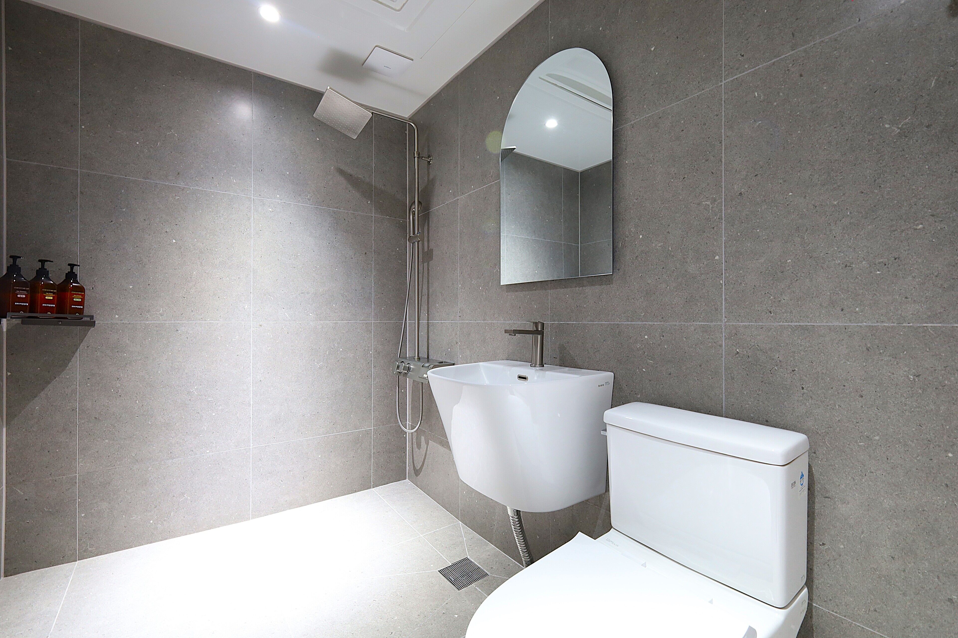 A modern bathroom with a shower, sink, and toilet.