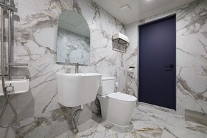 Ein Badezimmer mit Marmorboden, einem weißen Waschbecken, einer Toilette und einer dunkelblauen Tür.