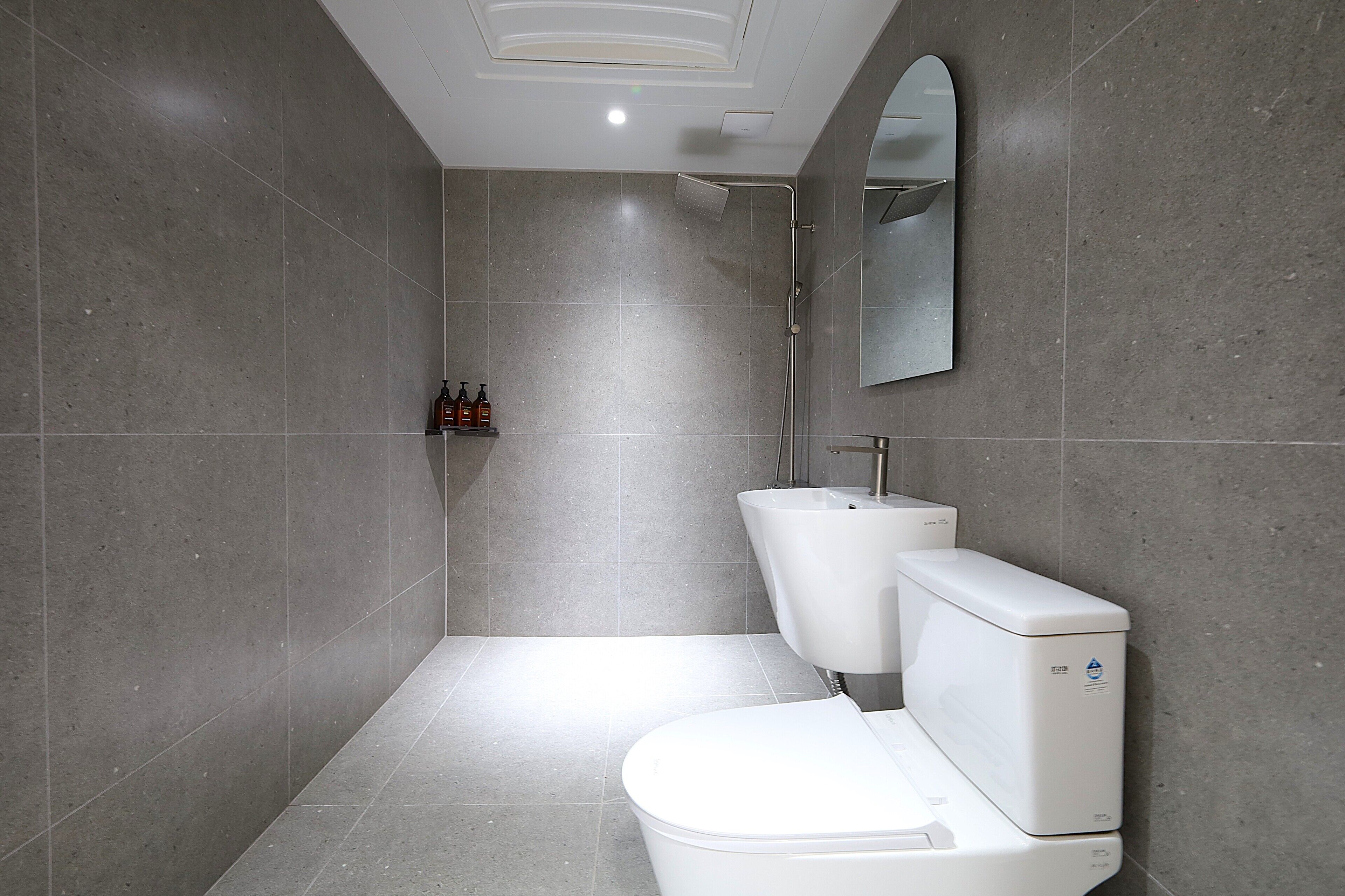 Een moderne badkamer met toilet, hygiëneschuimer en douche.