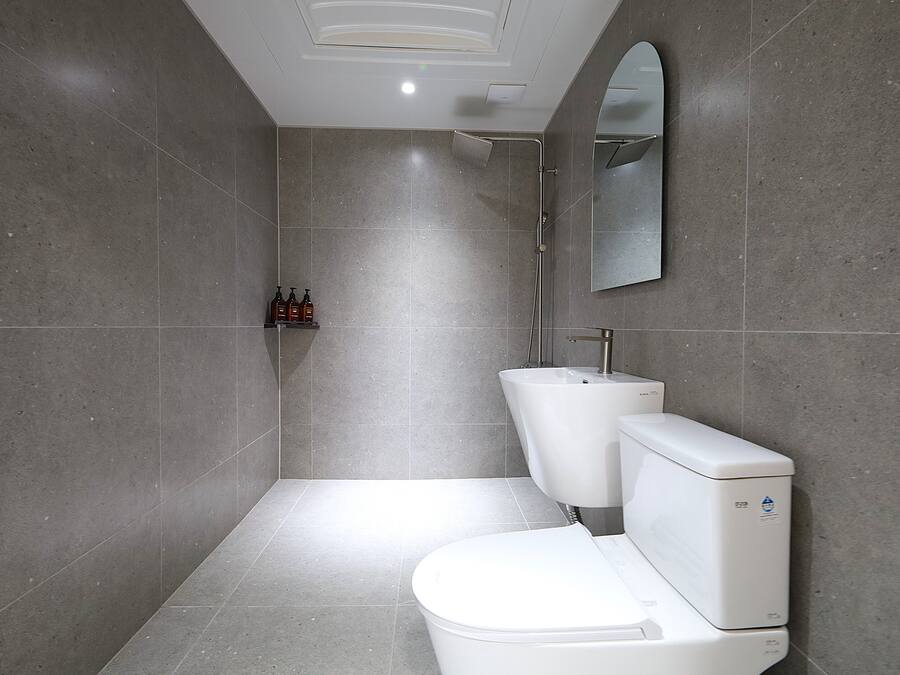 Een moderne badkamer met toilet, hygiëneschuimer en douche.