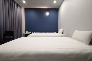 Ein Hotelzimmer mit zwei Betten, einem Schreibtisch mit Stuhl und einer Wandleuchte.