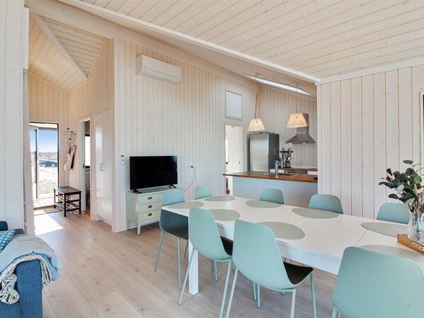 Una cocina moderna con comedor, paredes de madera y un ventanal grande.