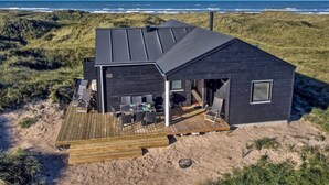 Uma casa moderna à beira-mar com varanda, mobiliário de exterior e vista para o oceano.