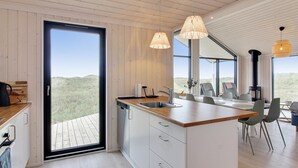 Cozinha moderna com uma ilha grande, teto de madeira e vista para o exterior.