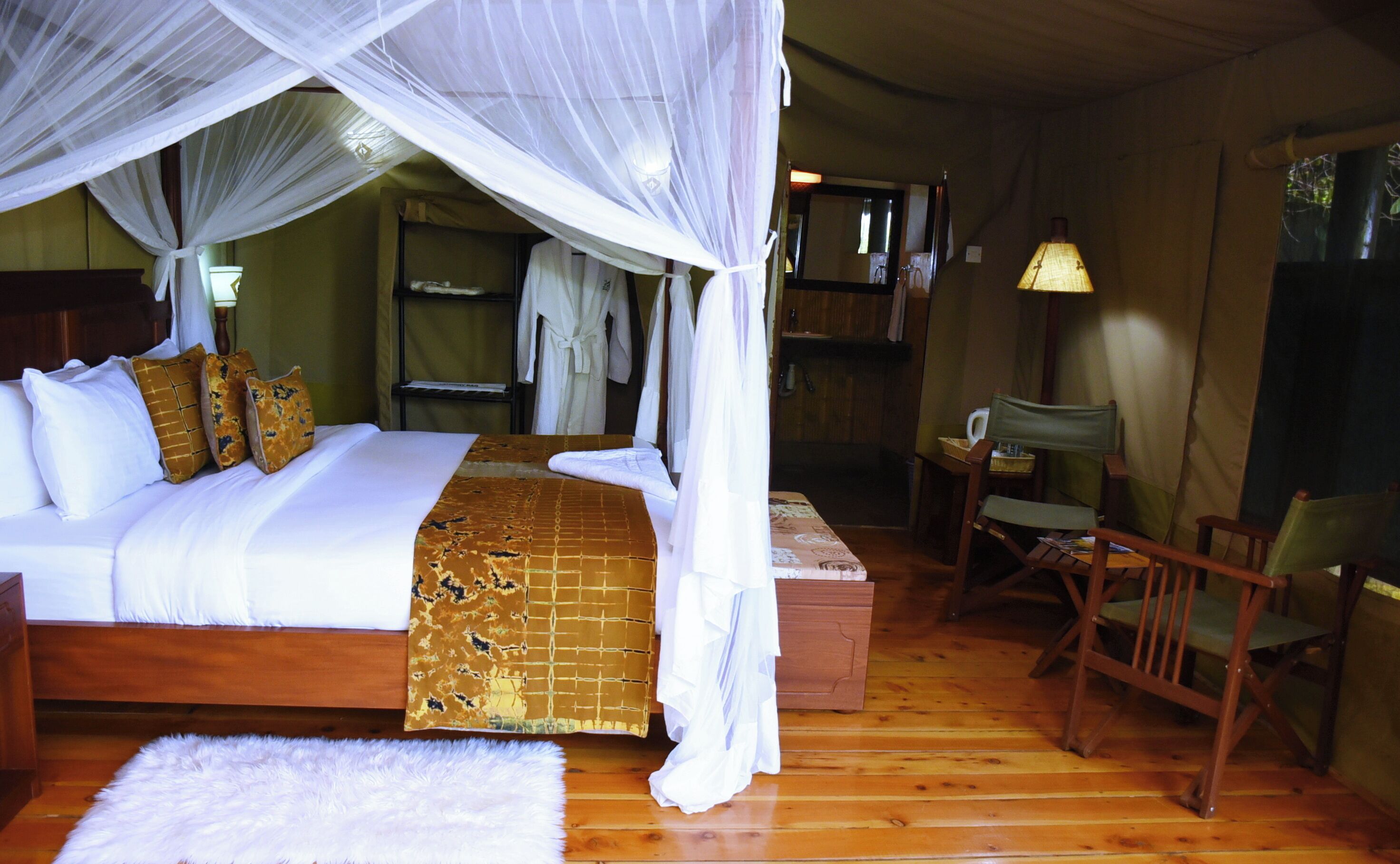 Une chambre à coucher avec un lit à baldaquin, un plancher en bois, une chaise et une table de chevet.