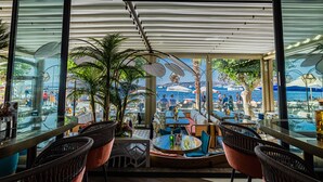 An indoor seating area with tables and chairs, a view of the sea, and potted plants. - Gözegir Hotel - Adults Only (Bodrum)