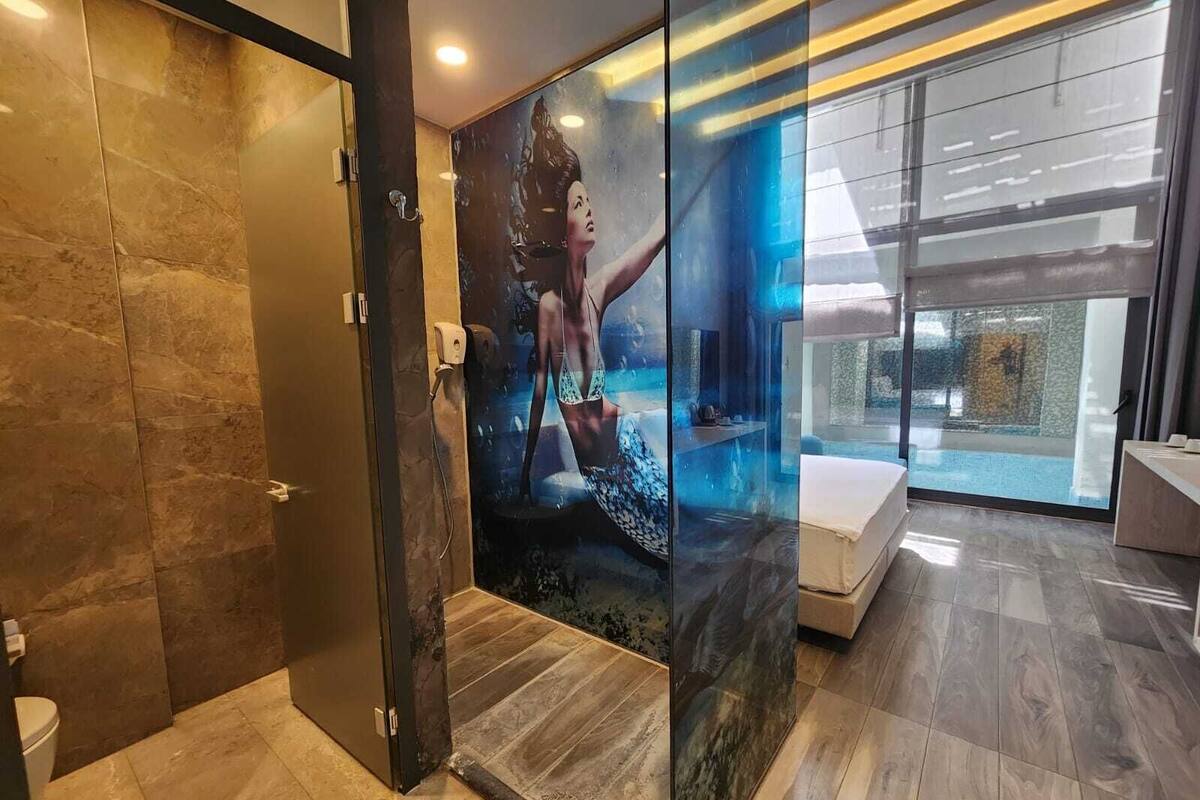Un baño moderno con cabina de ducha de vidrio, suelo de mármol y una ventana grande que ofrece vistas al exterior.