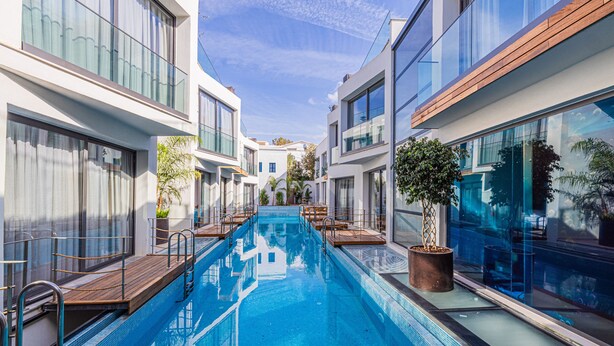 A modern hotel with a central swimming pool, large windows, and a clean, contemporary design. - Gözegir Hotel - Adults Only (Bodrum)