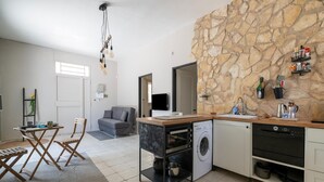 Una cocina compacta con pared de piedra, horno empotrado y lavadora.