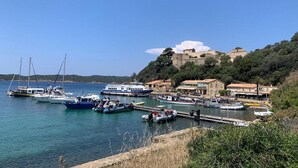 A coastal marina with boats docked, a historic building on a hill, and a clear blue sky. - Villa in Gaou with Sea View and Beach (Bormes-les-Mimosas)