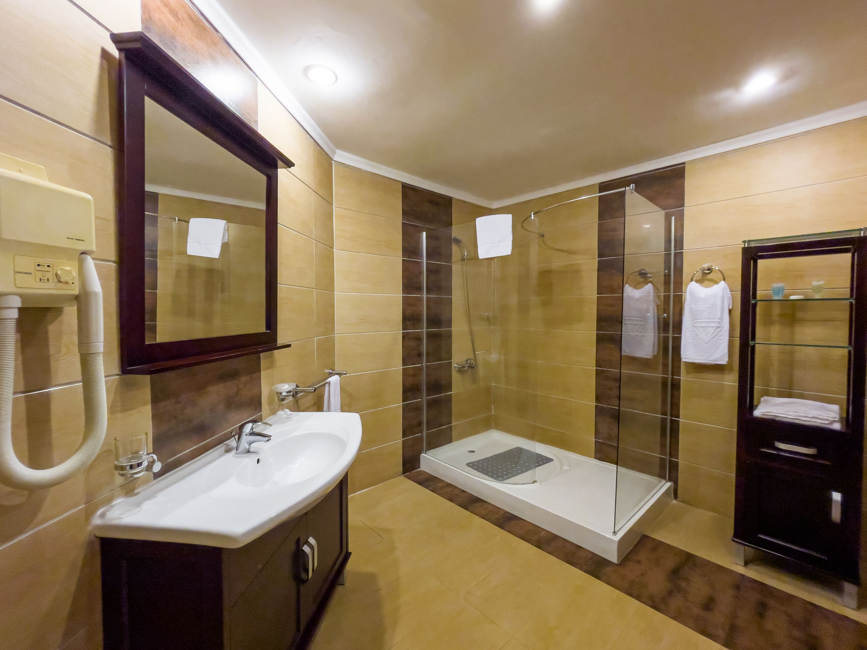 Un bany modern amb un lavabo, mirall, dutxa i moble de tocador amb vidre.