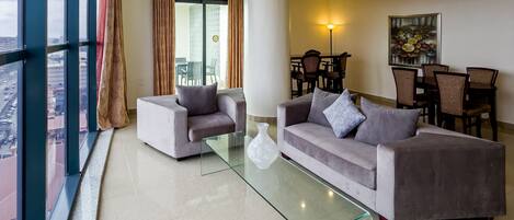 Una sala moderna con dos sofás, una mesa de centro de cristal y un comedor con sillas y una mesa.