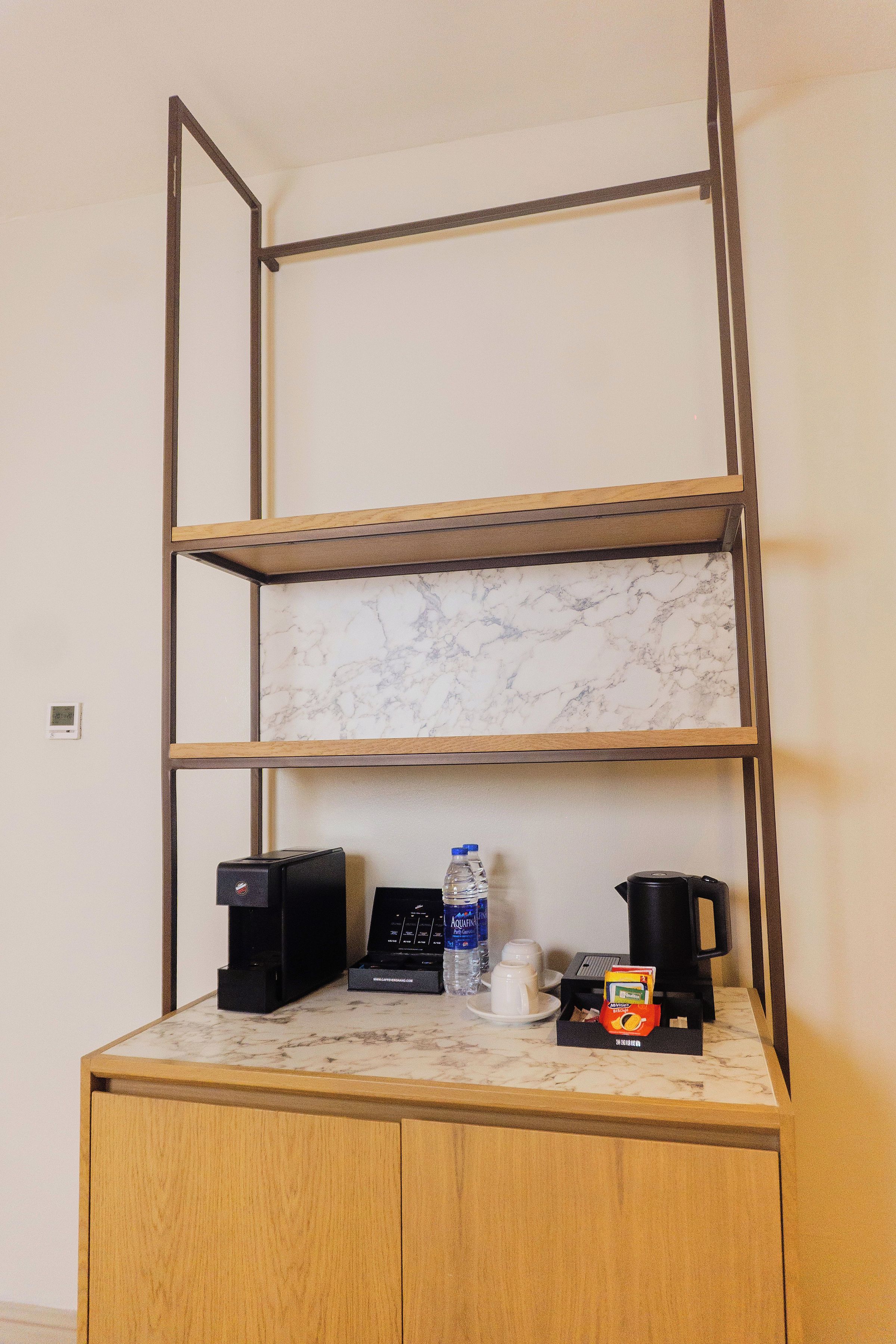Una kitchenette con encimera de mármol, cafetera, una botella de agua y máquina de café.