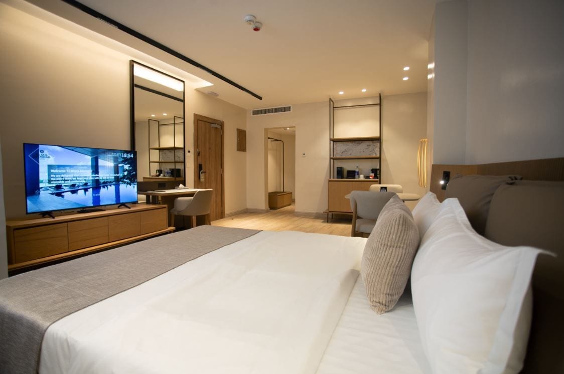 Una habitación de hotel moderna con una cama grande, un televisor, un escritorio y un espejo.