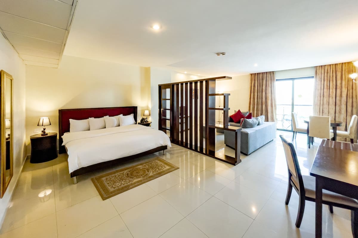 A modern hotel room with a large bed, a desk, and a dining area.