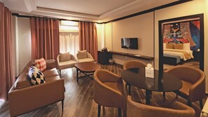Een moderne hotelkamer met een bank, fauteuils, een eettafel en een televisie.
