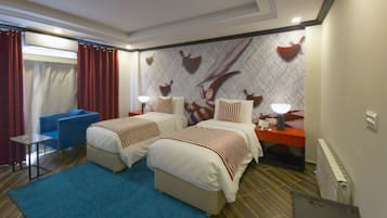 Quarto de hotel com duas camas, uma poltrona azul, uma mesinha e uma parede com detalhes decorativos.