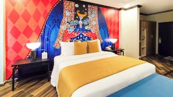Una habitación de hotel con una cama grande, dos mesitas de noche con lámparas, un tapiz en la pared y suelo de madera.