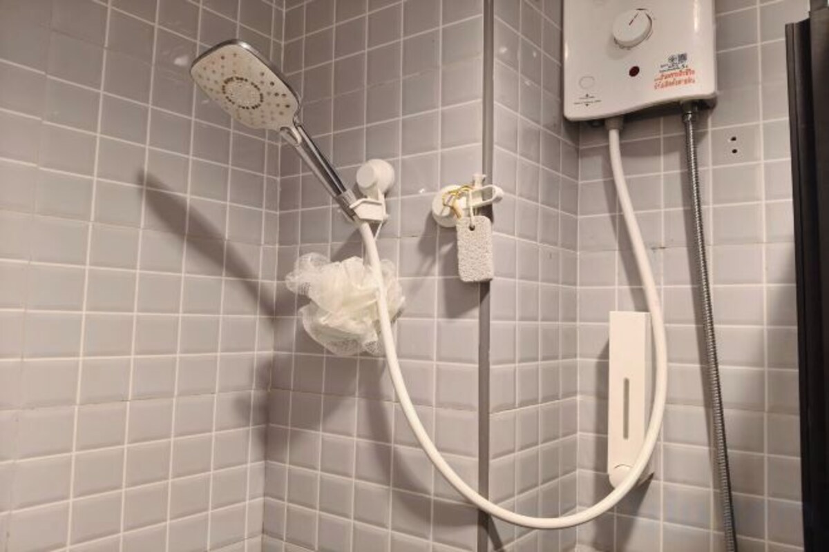 A shower with a handheld showerhead and a wall-mounted control panel.