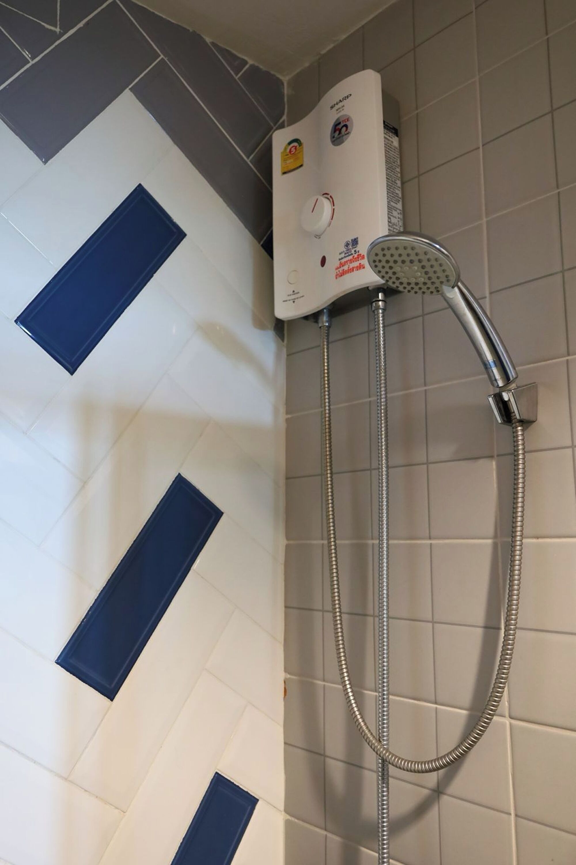 A shower with a control panel and a handheld showerhead.