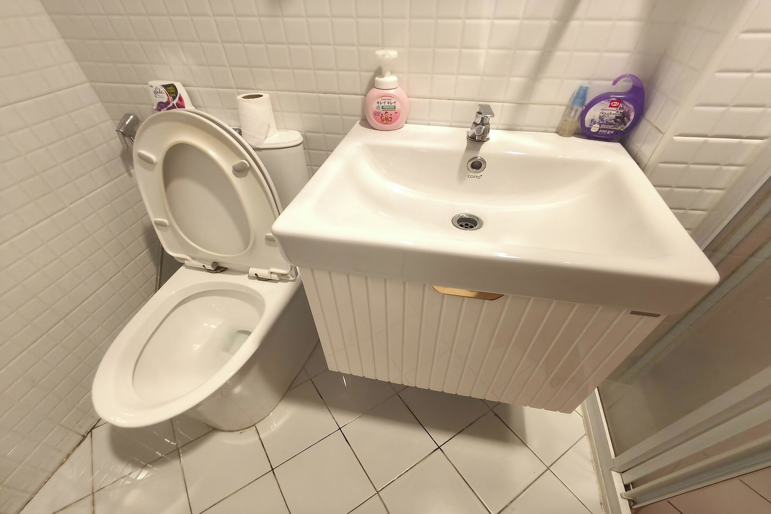 Un baño con inodoro, lavamanos y paredes de cerámica.