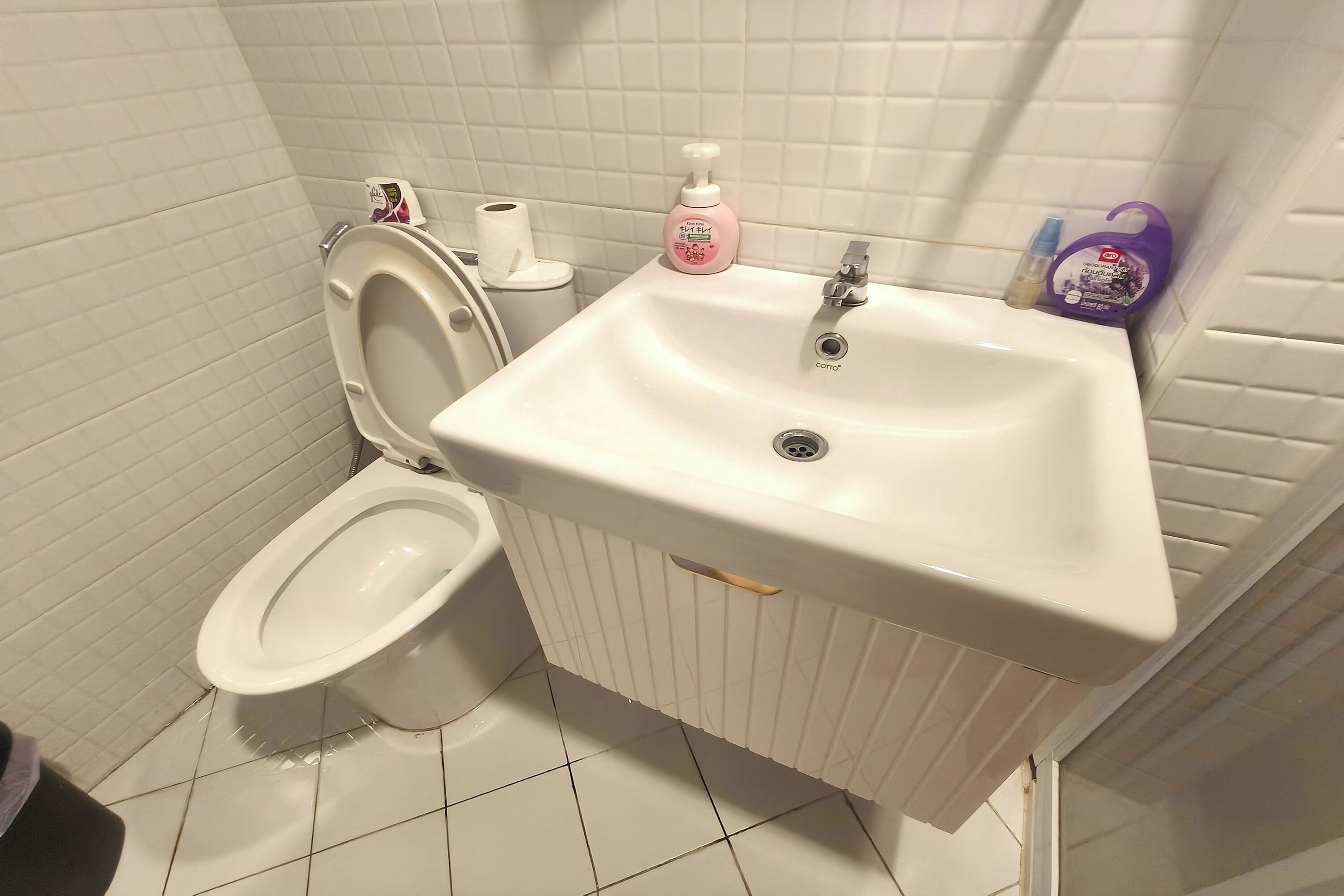 A bathroom with a toilet, sink, and two bottles of soap.