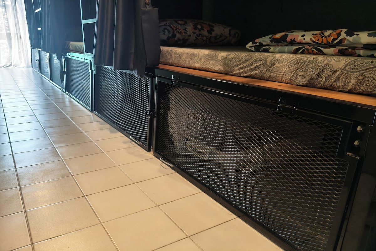 A room with a bed, a window with curtains, a tiled floor, and a mesh screen.