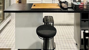 A compact kitchen with a central island, white cabinets, a microwave, and a chalkboard. - El biografo hostel (Bangkok)